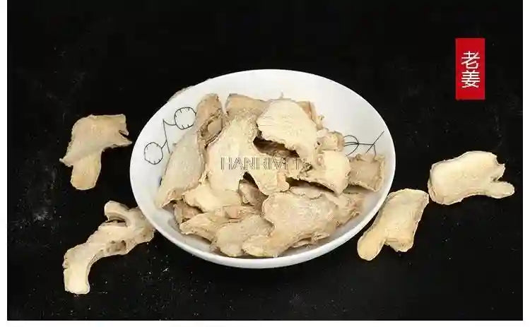 Dried ginger slices in a small white bowl for Chinese medicine foot bath soak on a black background.