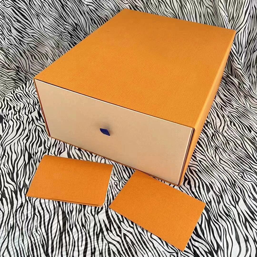 Orange luxury designer trunk box with beige drawer and blue tab, resting on a black and white zebra print fabric.