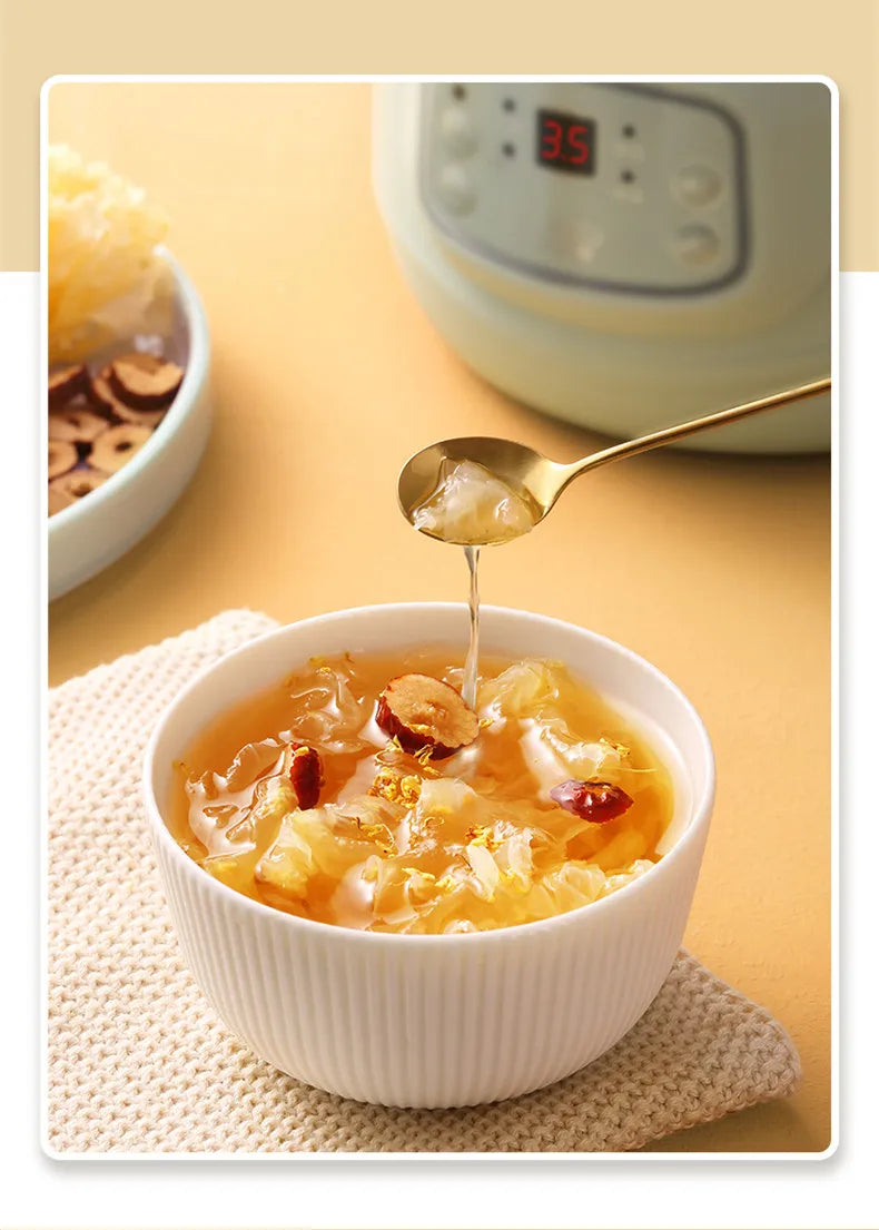 Bowl of orange stew being poured with a spoon, with mini cooker control panel in blur