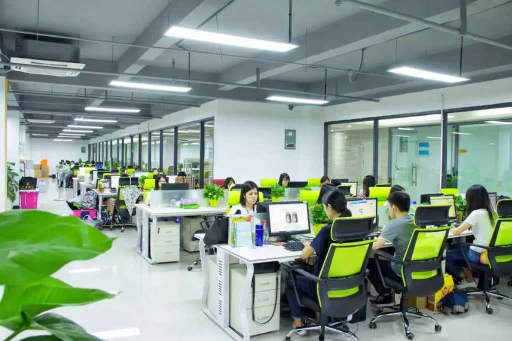Factory office production floor with workers seated at computers at workstations