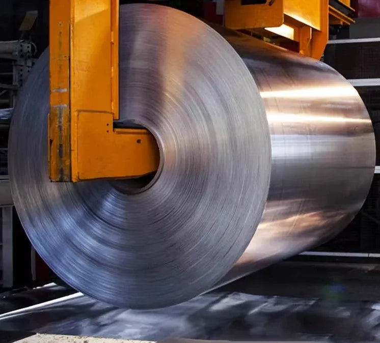 Large industrial roll of silver wire or ribbon material on a machine setup.