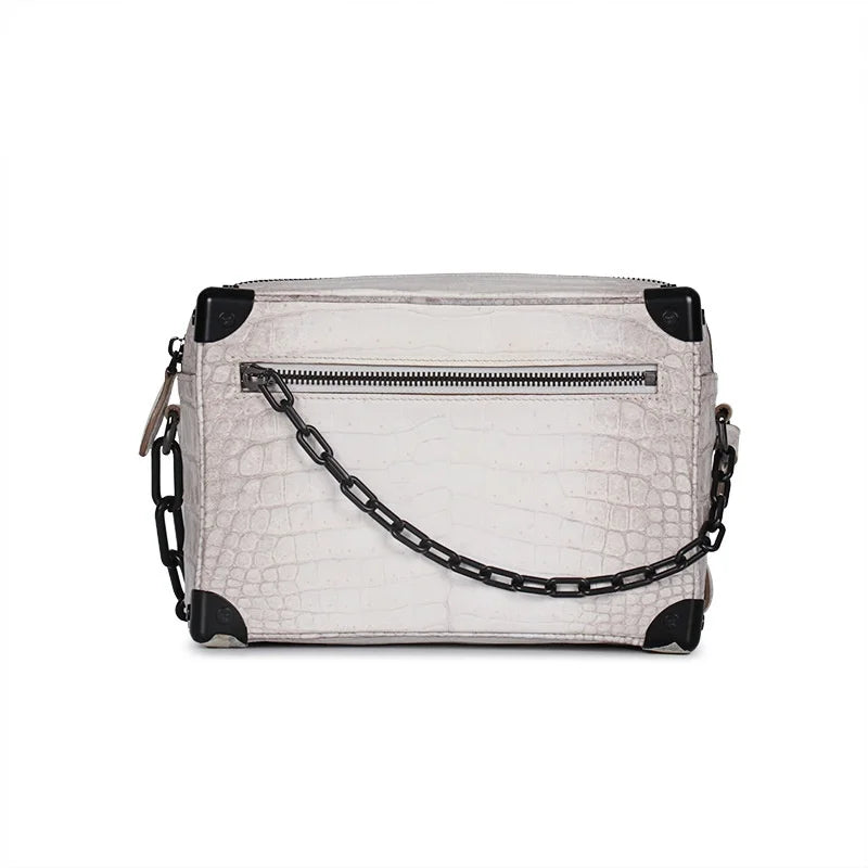 White Himalayan crocodile leather trunk bag with black chain strap and reinforced corner hardware. Luxury crossbody.