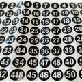 Macro view of self-adhesive round number stickers, black circles with white numerals 1–50