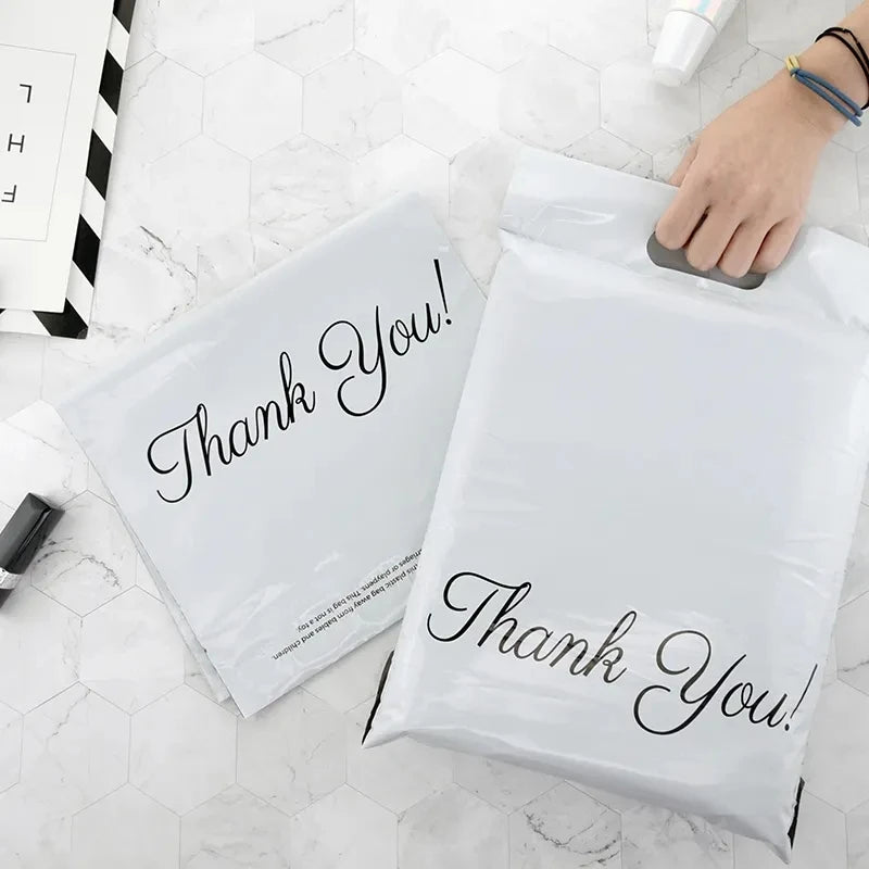 White poly mailer bags with handle, black “Thank You!” script print on both fronts.