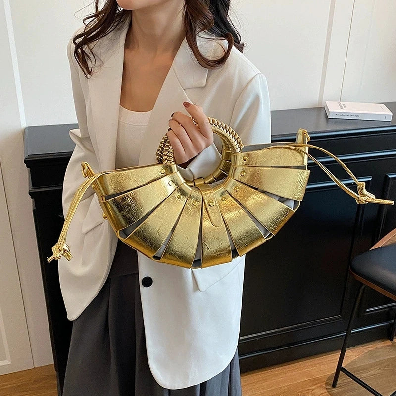 Metallic gold half-moon trunk handbag with structured cutout panels and a unique woven round handle.