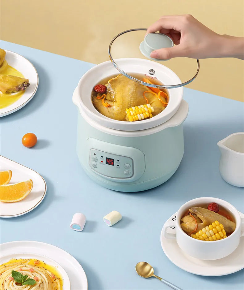 Mint mini stewing pot with clear lid lifted by hand, showing stew with corn and meat