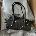 Black faux leather trunk-style shoulder tote with star and pearl studs, two handles, and top zip closure.