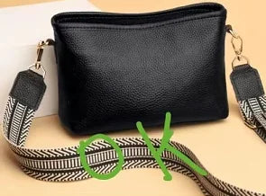 Black genuine leather women’s designer handbag featuring a wide, patterned guitar-style shoulder strap.
