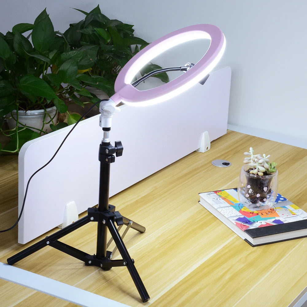 Pink ring light on a black tripod stand for desk-top photography and video lighting.