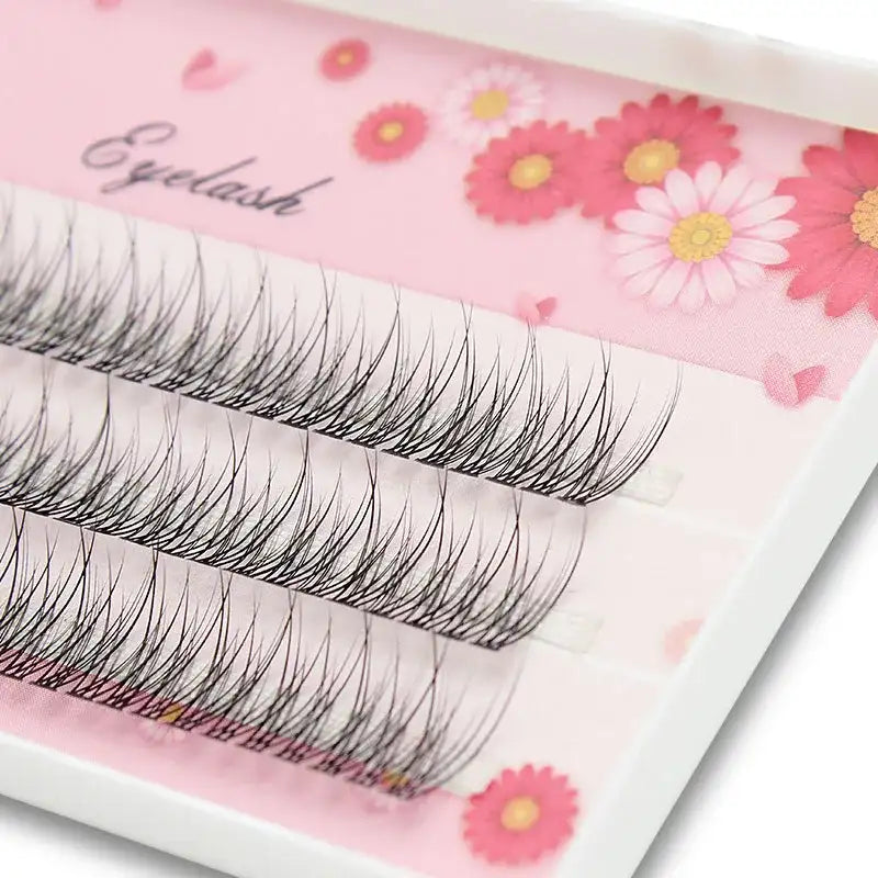 Black mink individual 3D flared eyelash clusters arranged on a pink floral patterned tray.
