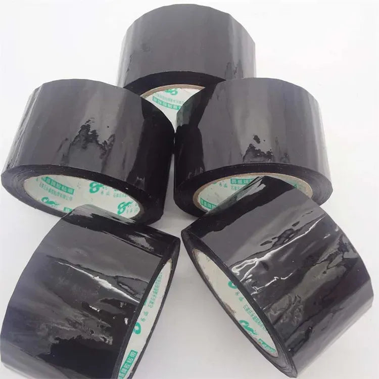 Black acrylic carton sealing tape rolls stacked, glossy adhesive surface