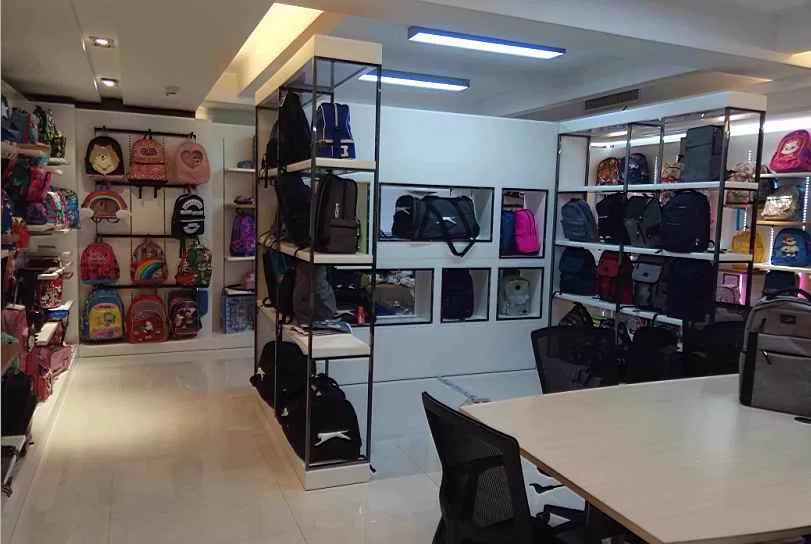 Showroom displaying various stylish luggage, trunks, and backpacks on modern retail shelving units.