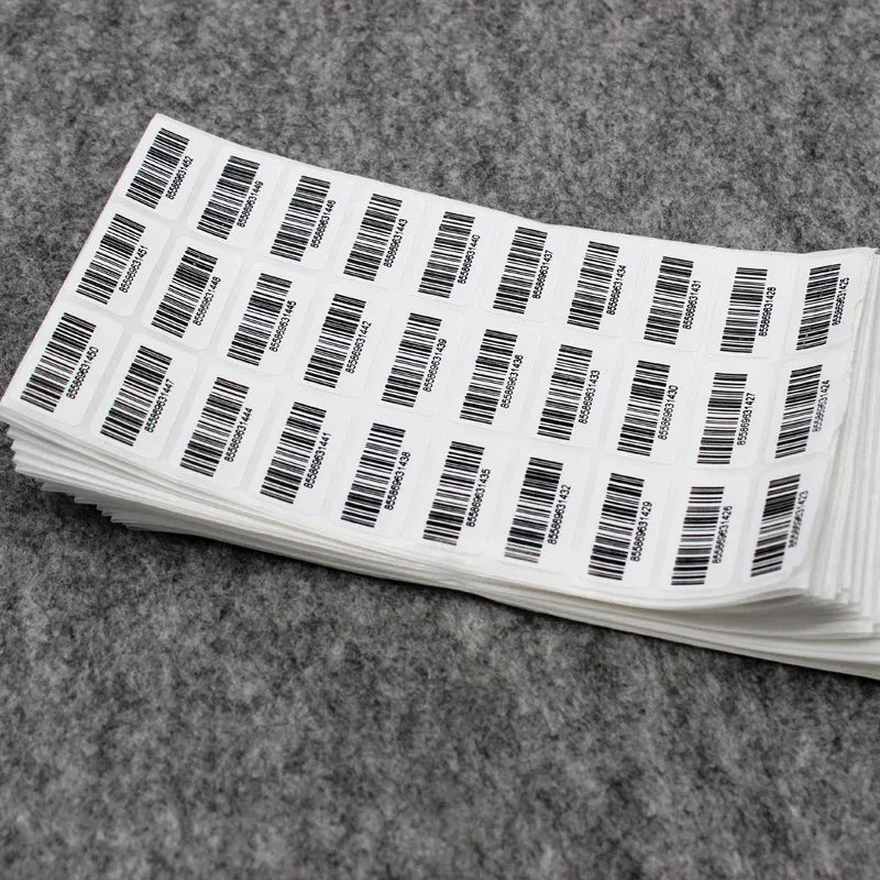 Stack of barcode inventory stickers, white rectangles with black barcodes and digits