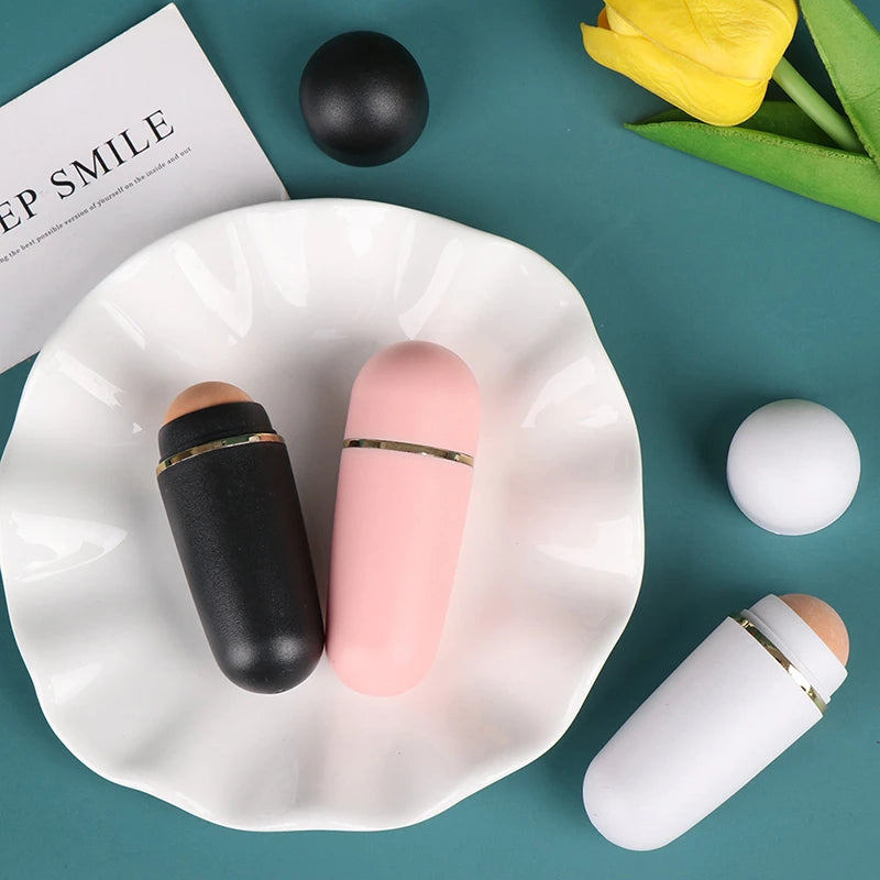 Three cylindrical face oil-absorbing rollers with natural volcanic stone balls in black, pink, and white.