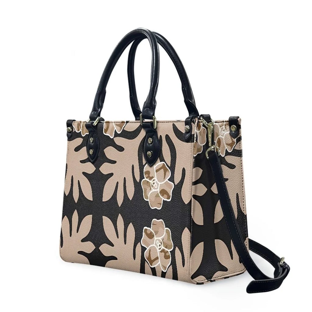 Luxury black and beige leather handbag with Polynesian Samoan tribal floral print, dual handles, and shoulder strap.