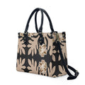 Luxury black and beige leather handbag with Polynesian Samoan tribal floral print, dual handles, and shoulder strap.