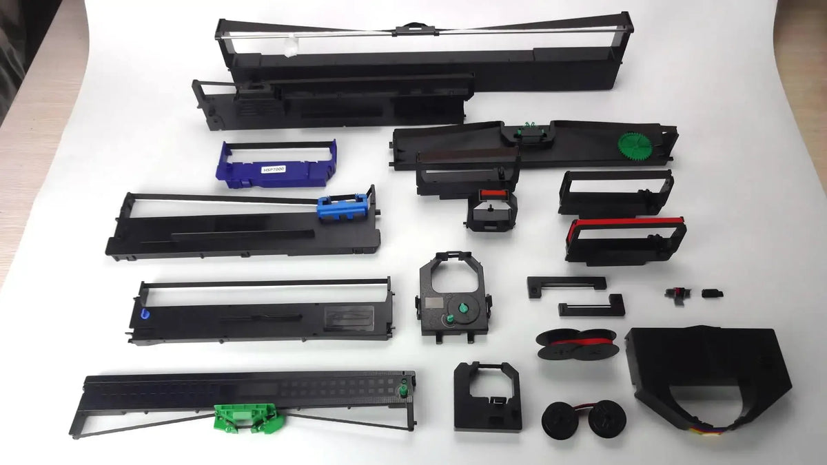 Assorted black thermal label cassette parts and reels layout, shown in an exploded view.