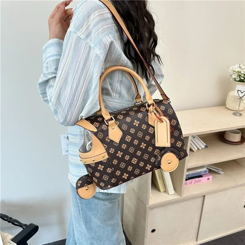 Brown PU leather trunk shoulder bag with floral pattern, tan trim, and novelty tricycle wheel accents for women.