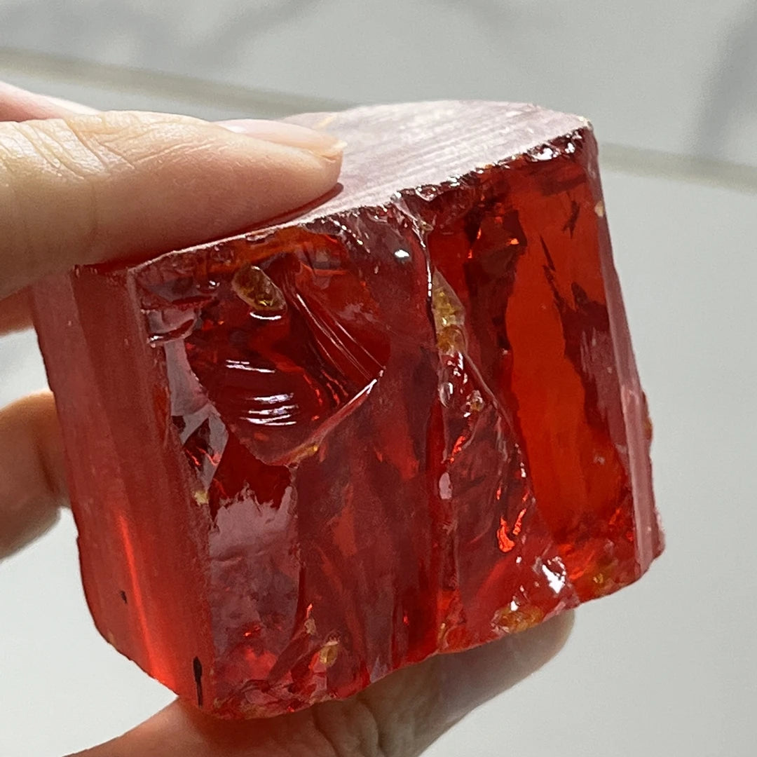 Loose red rough gemstone-style cubic zirconia crystal, uncut faceted piece held in hand