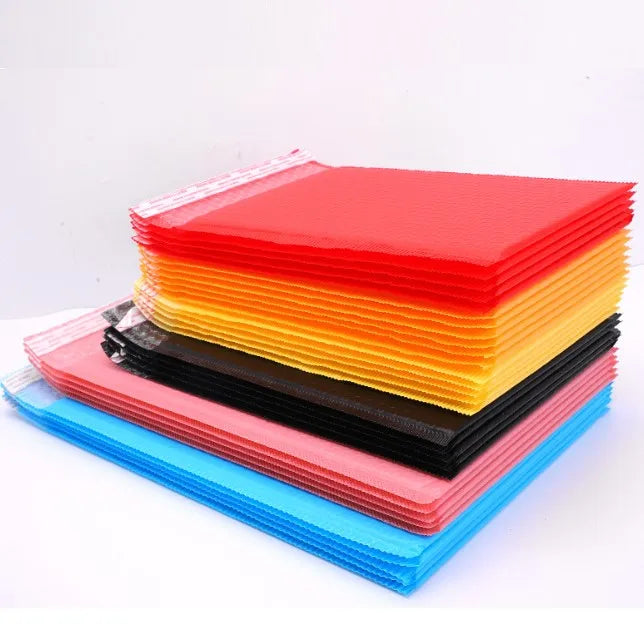 Stack of colorful plastic bubble mailer envelopes in red, orange, yellow, blue, and black