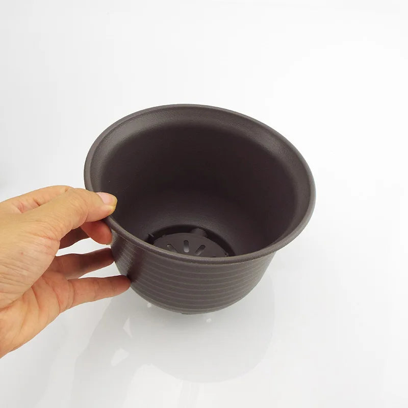 Dark gray plastic plant pot, close-up inside view with drainage insert.