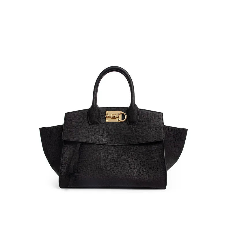 Black genuine leather designer trunk handbag with gold clasp hardware, dual top handles, and structured tote silhouette.