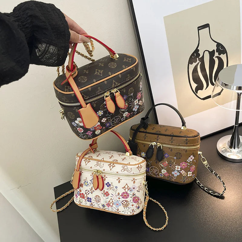 Designer vanity trunk handbags in leather with multi-color flower monograms, zip closure, and gold chain straps.