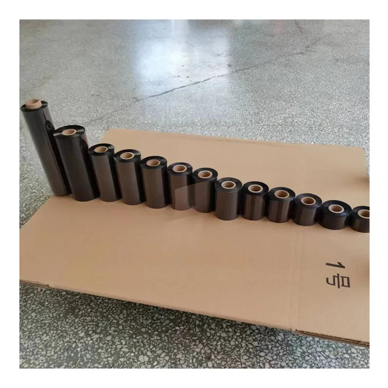Row of black thermal transfer ink ribbon rolls on cardboard, roll cores visible