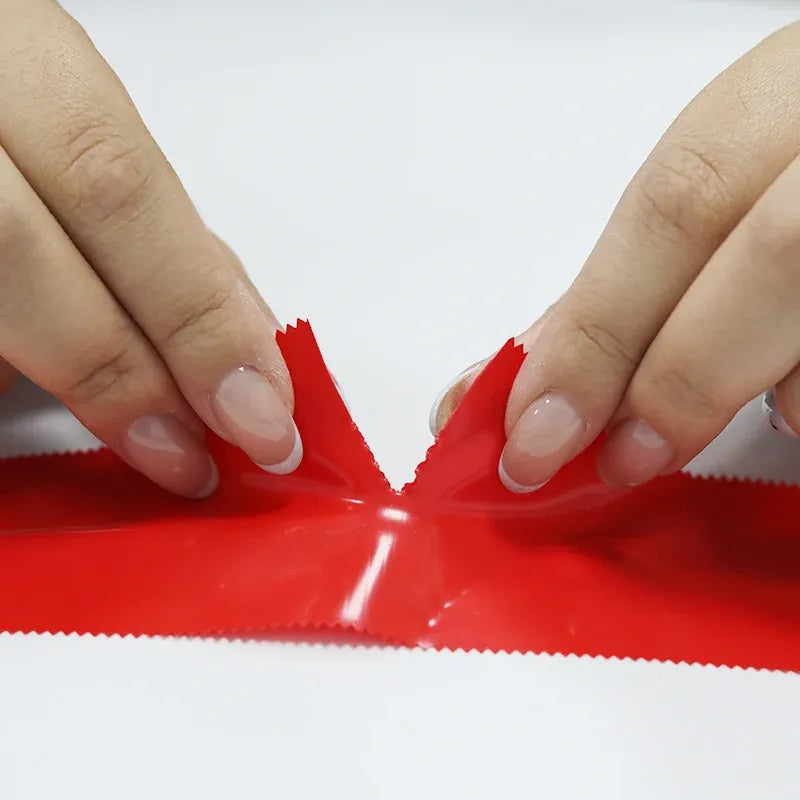 Hands pressing red adhesive tape seam, tape strip laid flat
