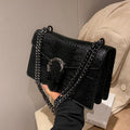 Black crocodile-embossed leather luxury crossbody bag with silver chain strap and ornate metal buckle clasp.