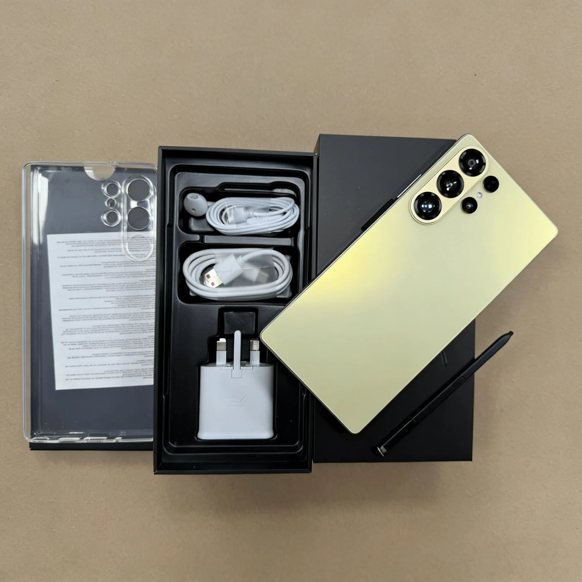 Unlocked smartphone in gold-green with four rear cameras; open box showing charger