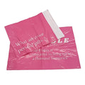 Pink poly mailer bags with white logo and quote text, one bag partially open