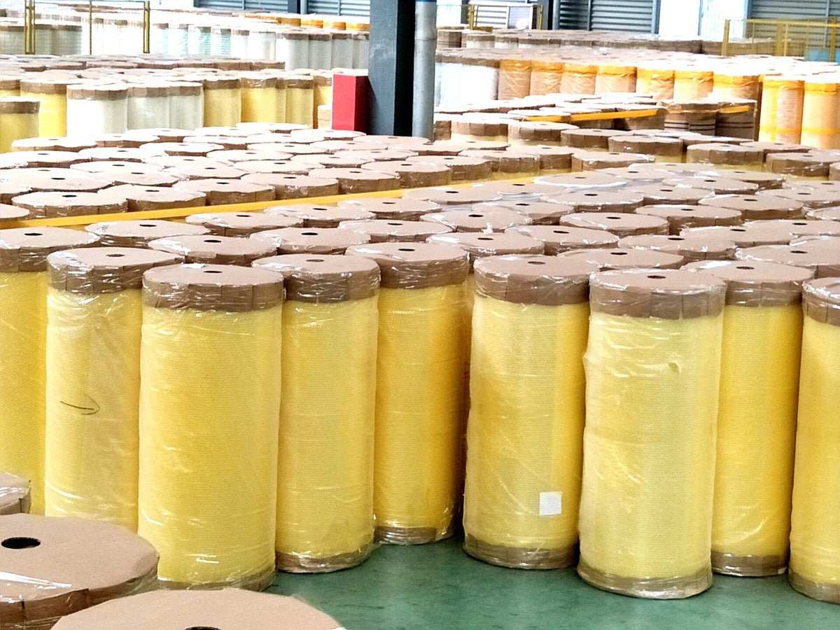 BOPP adhesive tape jumbo rolls, yellow rolls with brown-wrapped sections in warehouse