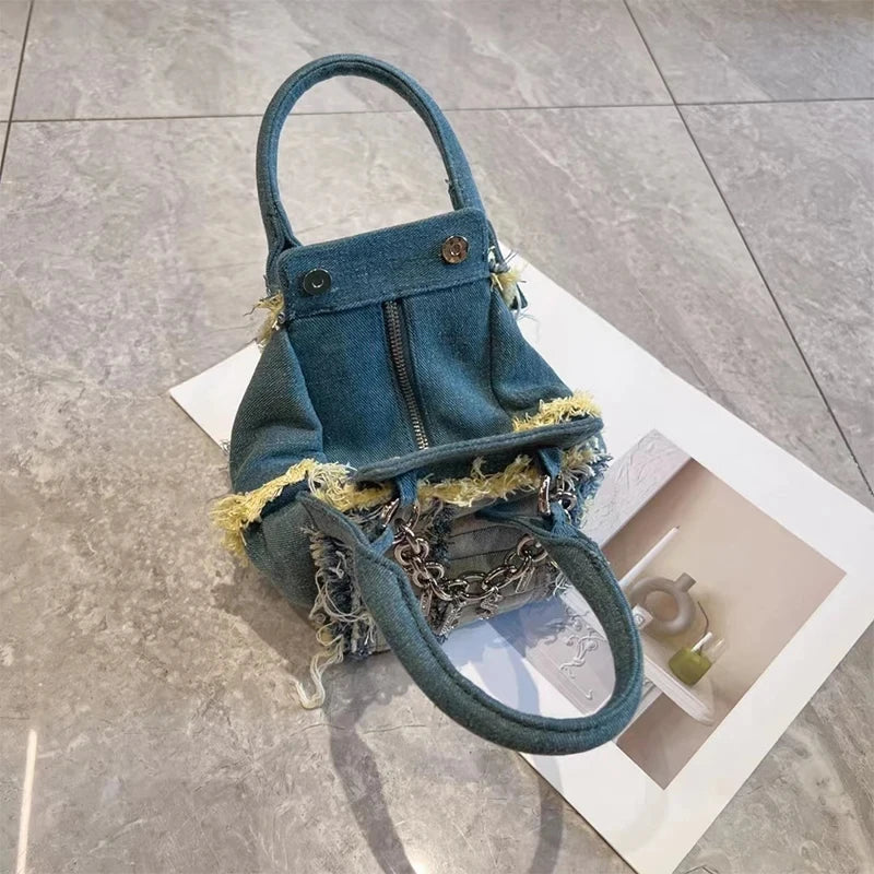 Vintage washed denim hobo handbag with frayed yellow edges, silver chain detail, and dual top handles.