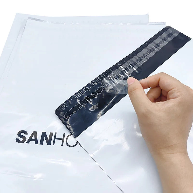 White shipping mailer bag with diagonal navy strip held by a hand