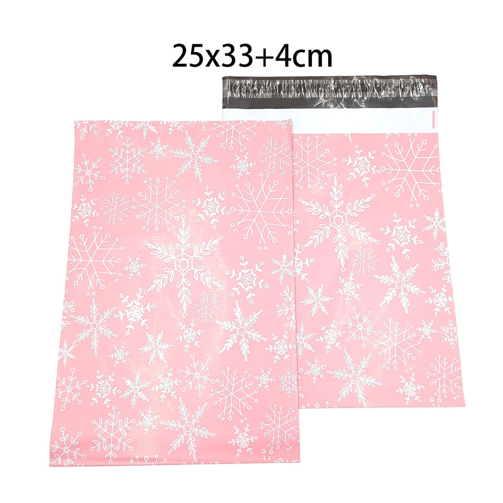 Pink poly mailer with white snowflake pattern and top handle cutout; size 25x33+4cm
