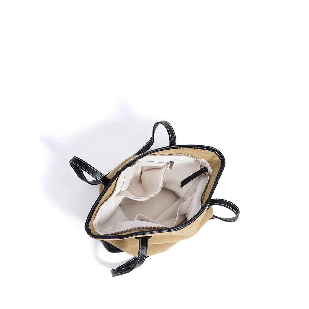 Vintage beige suede underarm tote with black leather trim, minimalist design, and white fabric interior pockets.
