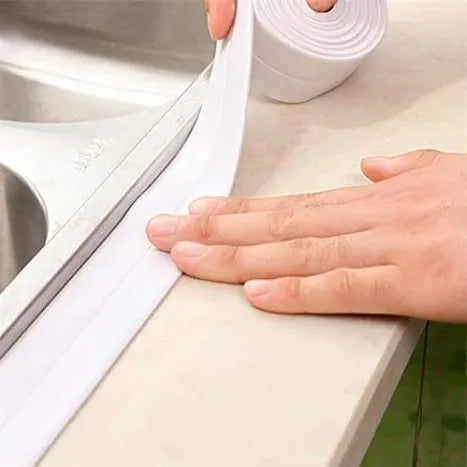 White waterproof corner sealing tape pressed by hand along bathtub rim