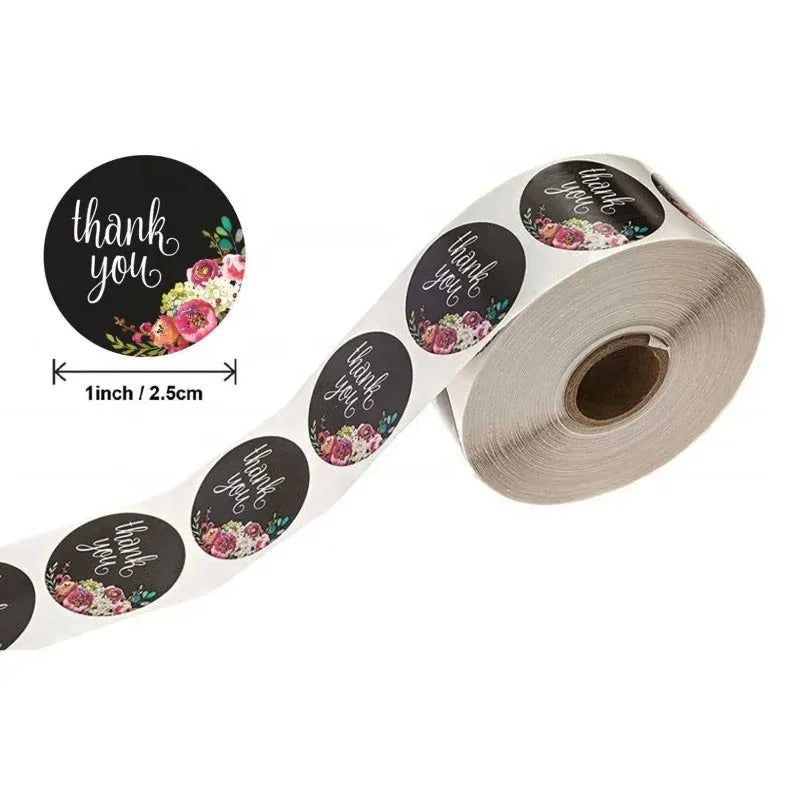 Round thank you stickers with pink floral wreaths on black, on a roll