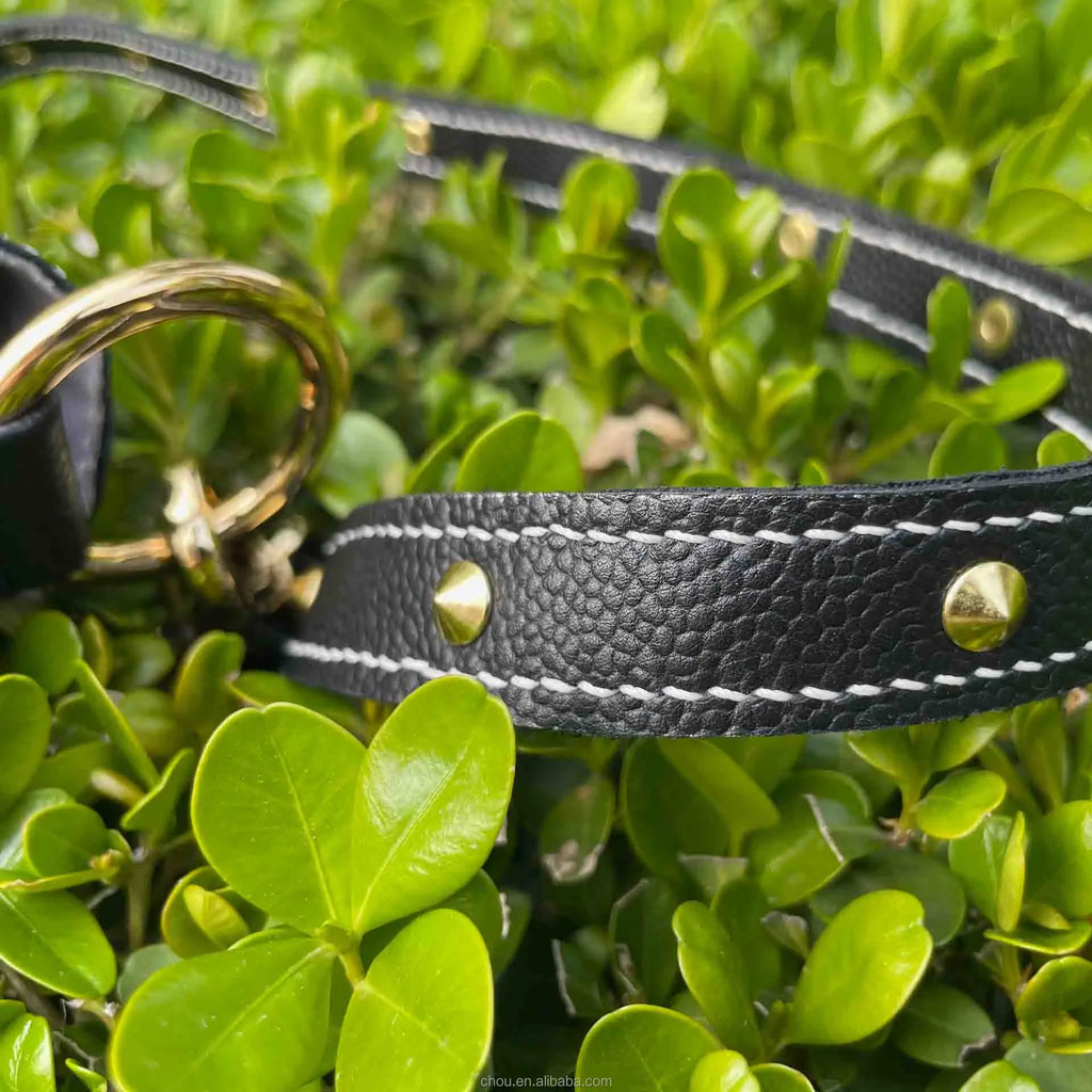 Black pebbled calf leather handbag strap with white contrast stitching, gold stud accents, and gold ring hardware.