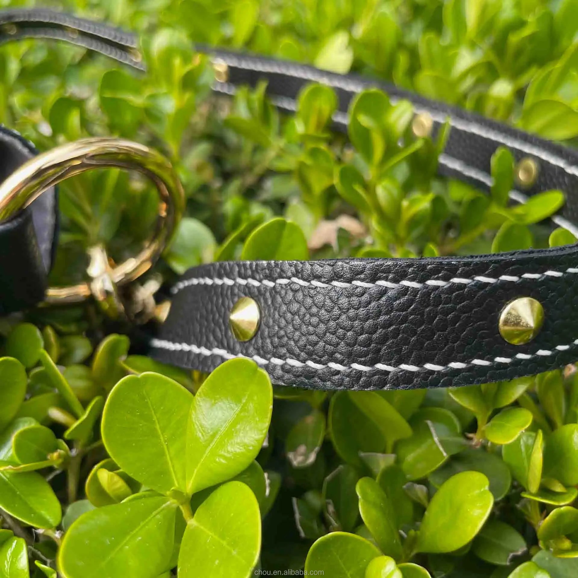 Black pebbled calf leather handbag strap with white contrast stitching, gold stud accents, and gold ring hardware.