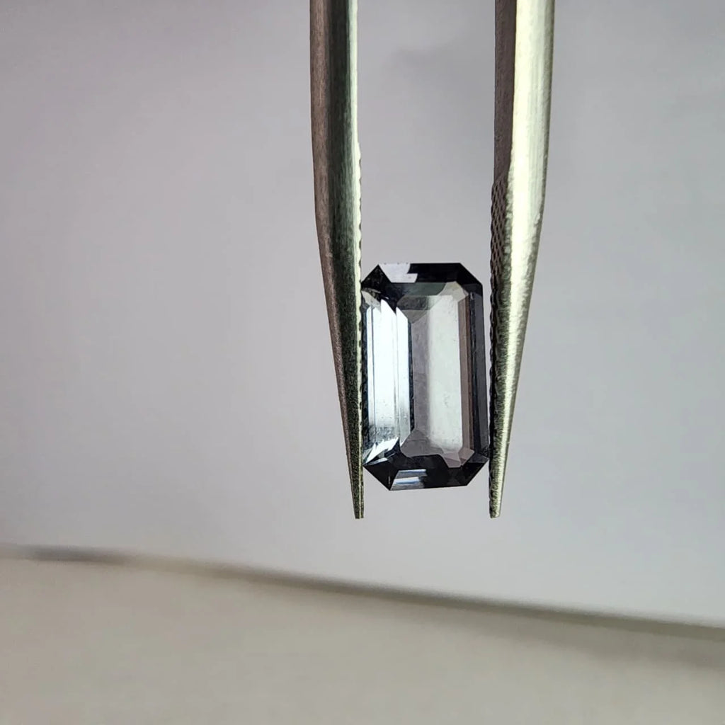 Dark gray emerald-cut spinel gemstone, prong-held close-up