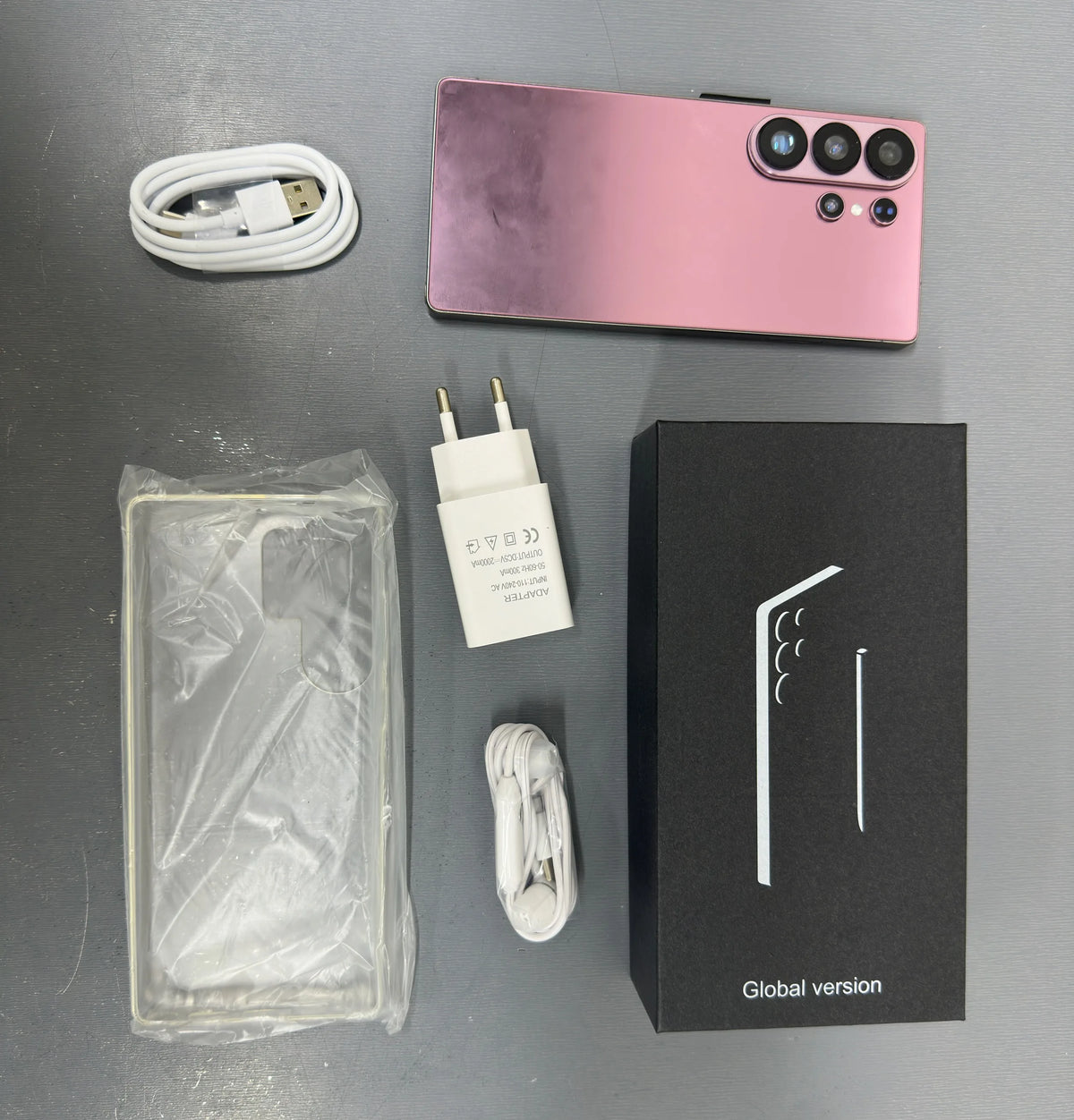 Smartphone with pink back, charger, cable, and global version box with phone case