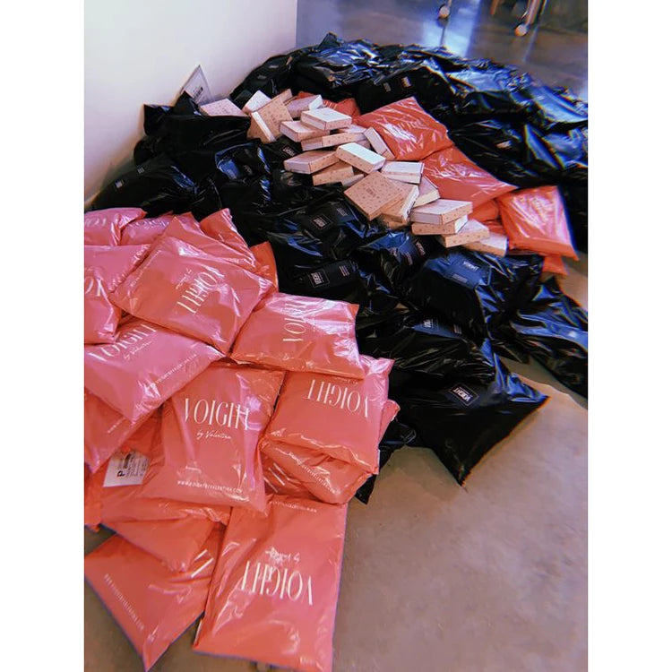Pile of compostable courier mailer bags in black and orange, side by side