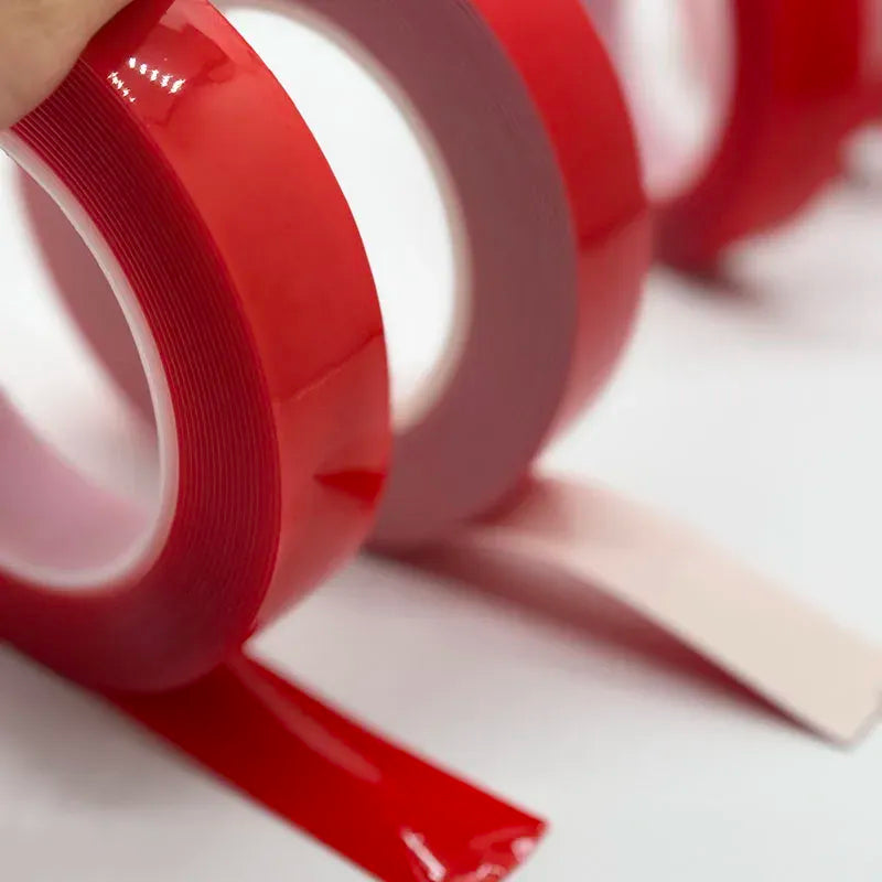 Red double-sided acrylic foam tape roll with exposed adhesive strip edge