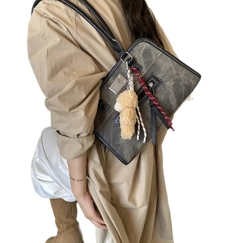 Large grey soft leather tote bag with shoulder straps, metallic accents, and a plush keychain charm.