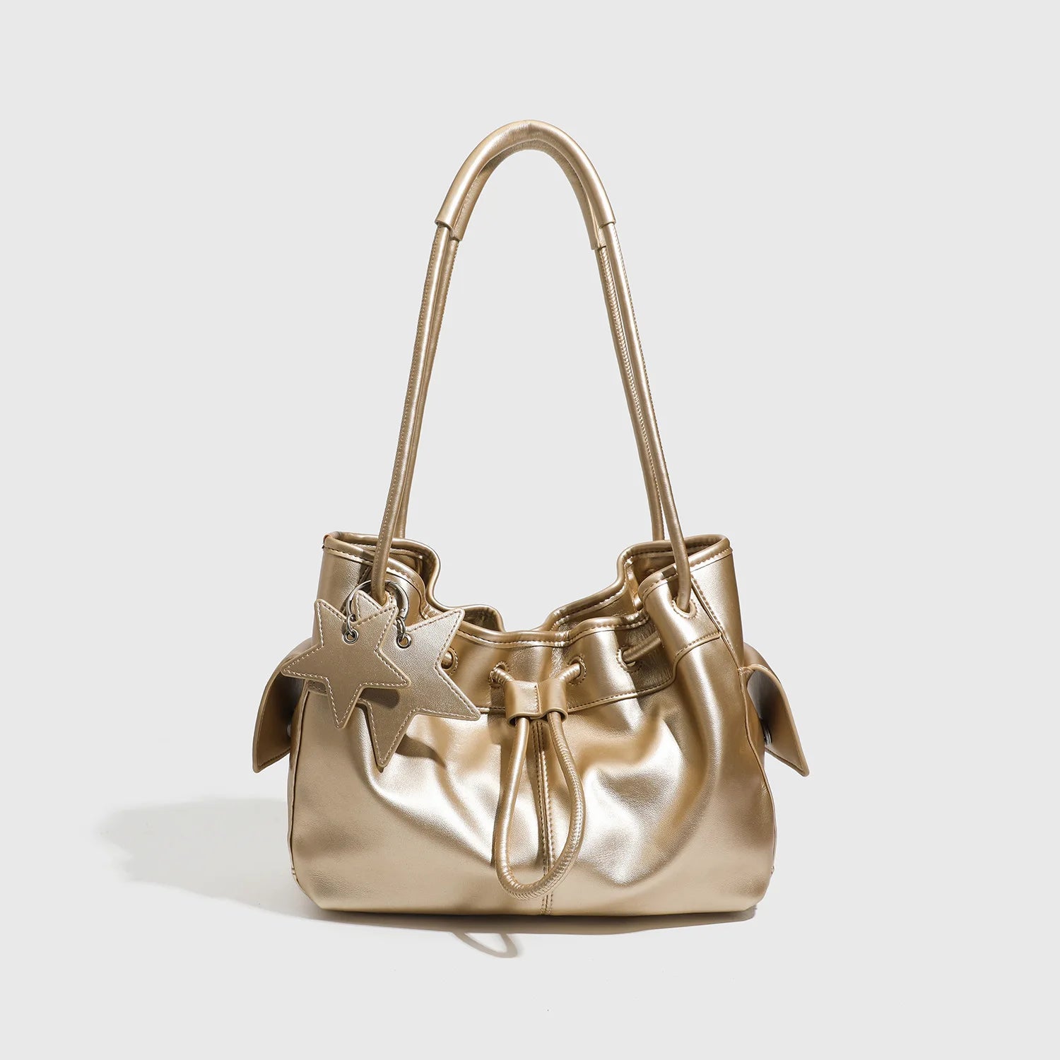 Metallic gold designer shoulder bag with drawstring closure, dual straps, and star charm for a chic commuting look.