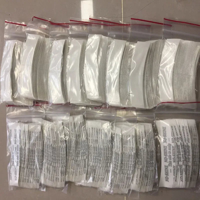 Packaged white adhesive tape strips with printed labels, stacked in rows