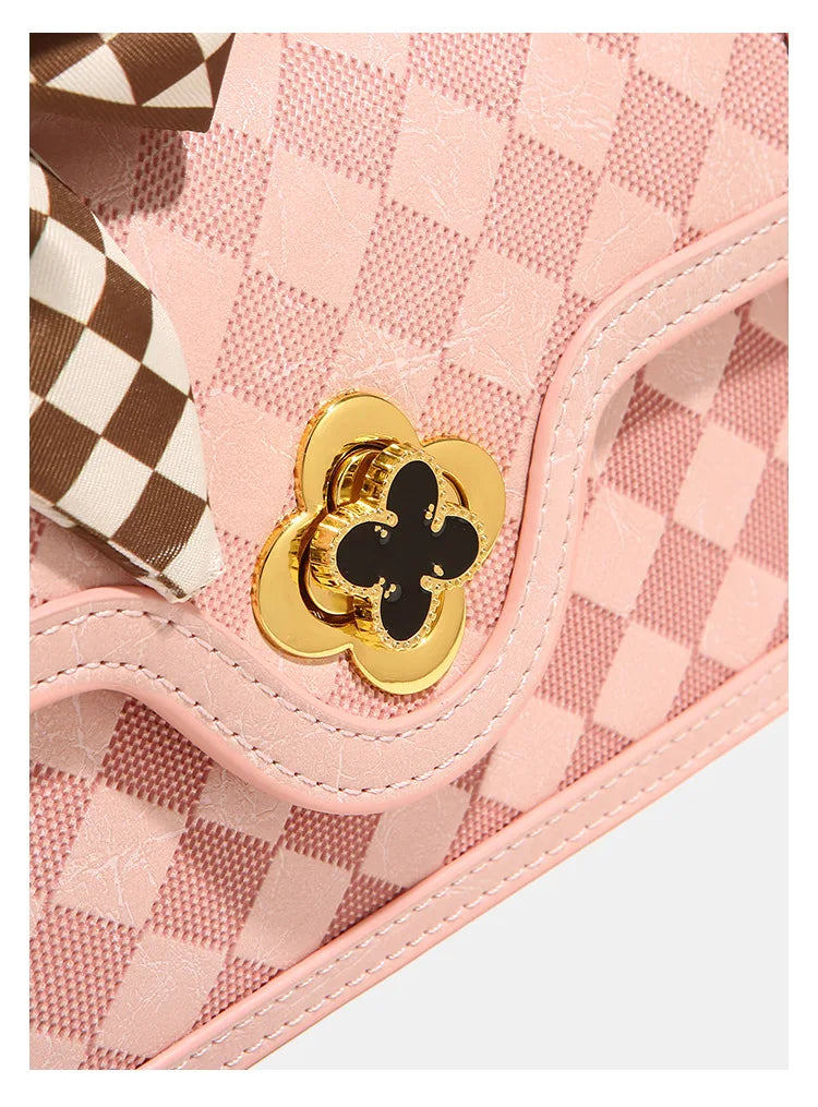 Pink plaid leather messenger handbag featuring a gold flower-shaped lock and a brown-and-white checkered ribbon bow.