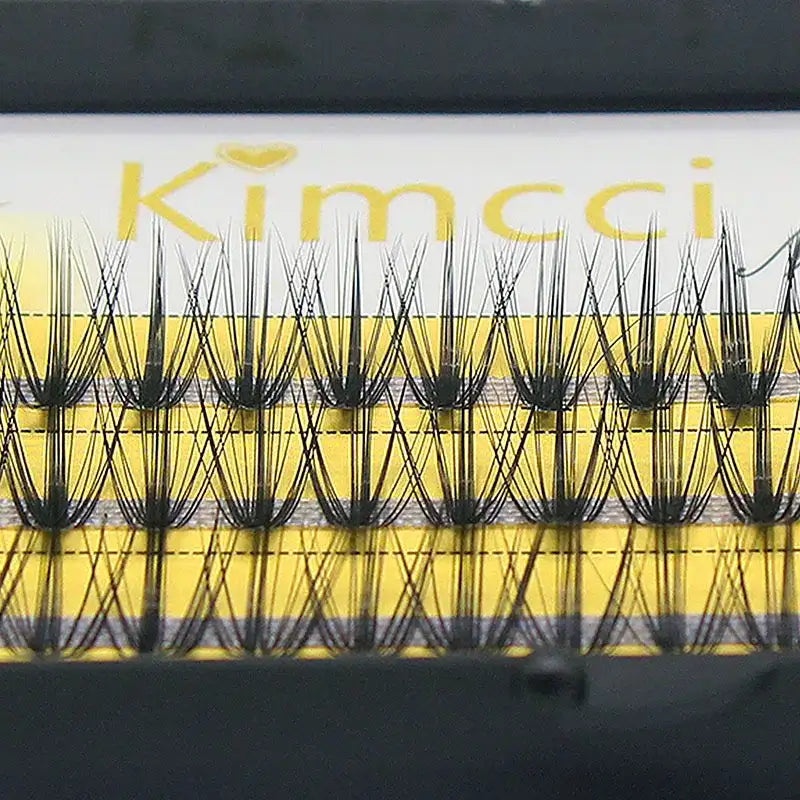 Close-up of black 20D Russian volume eyelash clusters on a yellow professional tray.
